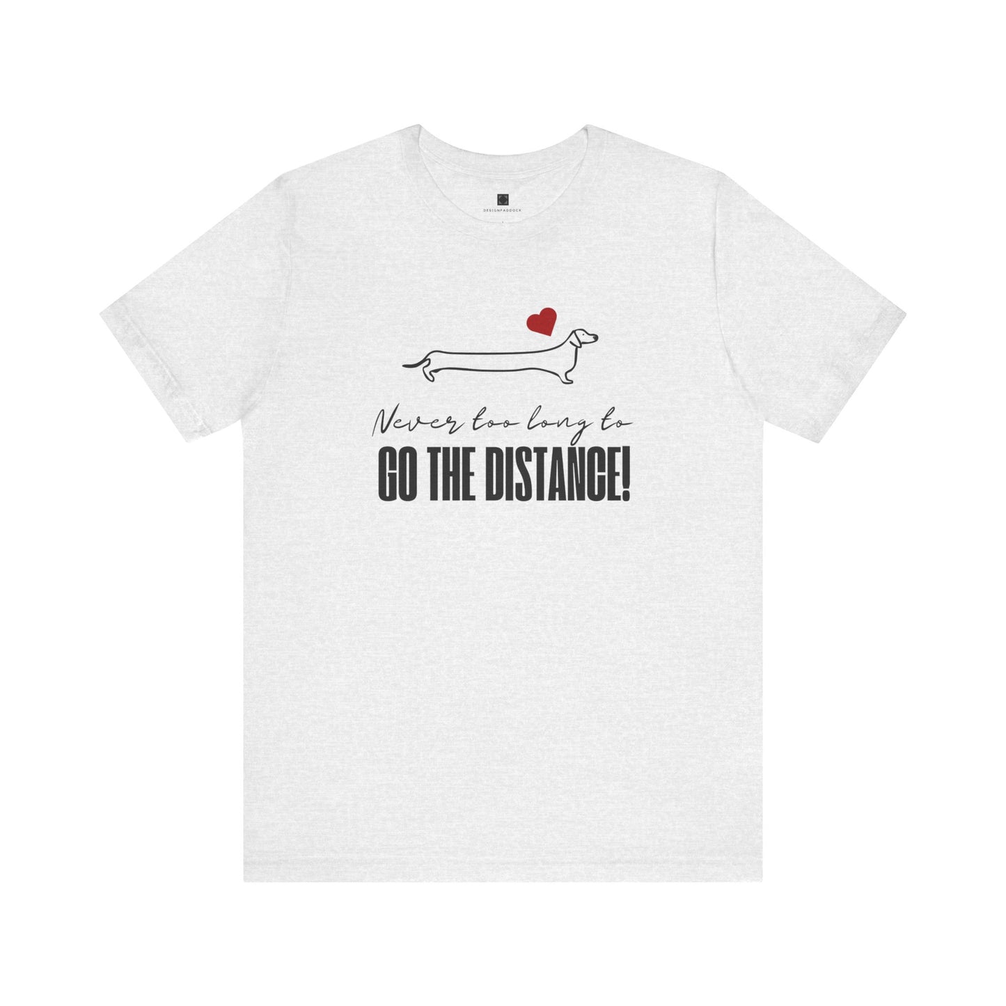 Ash style Dachshund t-shirt laid flat on a white background, featuring a minimalist Dachshund design, red heart, and the phrase “Never too long to GO THE DISTANCE!”