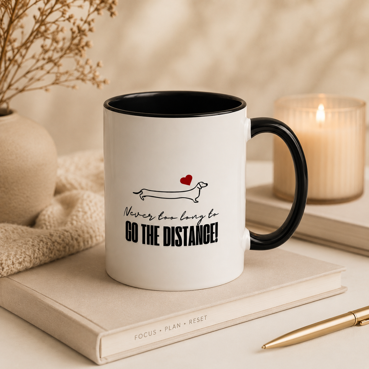 White ceramic dachshund mug with black handle styled in a cozy neutral workspace with soft candlelight, beige planner, dried florals, and gold pen.